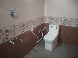 a bathroom with a white toilet in a room at Gubbikanta Homestay in Aralagodu