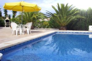 a table and chairs with an umbrella next to a swimming pool at Casa Sara - Private Villa with Private Pool in Ciudad Quesada