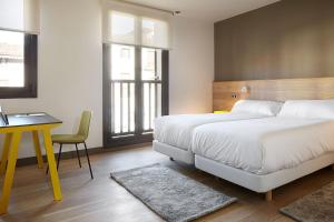 een slaapkamer met 2 bedden, een tafel en een bureau bij Hotel Imaz in Segura