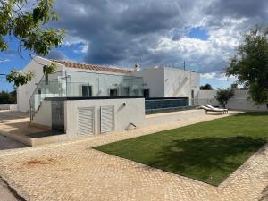 ein weißes Haus mit Glastüren und einem Hof in der Unterkunft Monte Gerações - Complete House - Heated pool - Typical Algarvian - close to Quinta Lago Vale Lobo and Vilamoura in Almancil