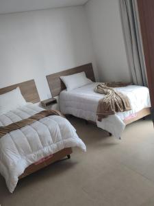 Un dormitorio con dos camas con sábanas y almohadas blancas. en Boa Esperança Apart Hotel, en Boa Esperança