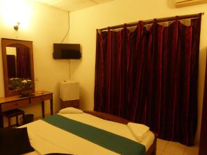 a bedroom with a bed and a window with red curtains at Snowdrop in Negombo