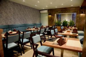 a dining room with wooden tables and chairs at Golden Heritage Dapoli in Dapoli