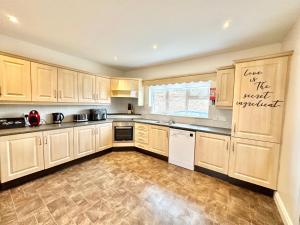 Relax in Spacious Style with Stunning Views- Drim Cottage في Malin Head: مطبخ مع خزائن خشبية وأرضية من البلاط