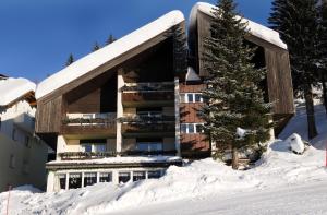 a snow covered building with a tree in front of it at Haus Hoffmann in Sonnenalpe Nassfeld