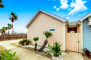 a house with palm trees in front of it at Sail Away at Pirate's Bay Unit 113 in Port Aransas