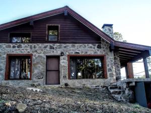 a stone house with windows on a hill at Cabaña villa alpina Mantillo de bosque in Villa Alpina