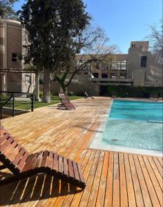 een houten terras met 2 stoelen en een zwembad bij Excelente Dpto, Gran vista MDZ in Mendoza