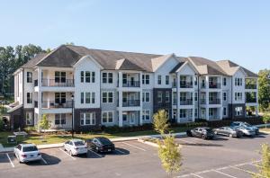 ein Mehrfamilienhaus mit auf einem Parkplatz geparkten Autos in der Unterkunft Charming, New Apt, Pool, Long Stays in Athens