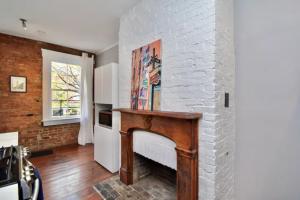 a living room with a fireplace and a white brick wall at Walk to Everything - Sports, Food, Music, Downtown in Cincinnati