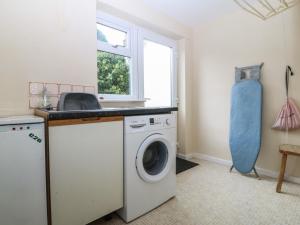 a laundry room with a washing machine and a window at Ty Nant in Abersoch