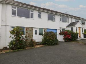 a white house with flowering bushes in front of it at Ty Nant in Abersoch