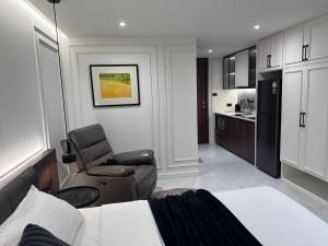 a bedroom with a bed and a chair and a kitchen at Chill Chill at Nimman in Chiang Mai