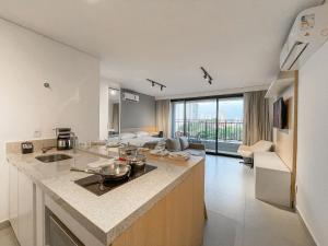 a kitchen with a counter and a living room at Vista XV by Housi in Campo Grande
