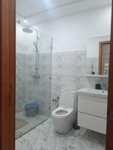 a white bathroom with a toilet and a shower at plage Taït club omeGa in Andalouciene