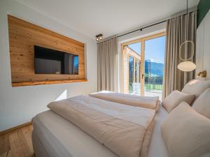 a bedroom with a bed with a tv and a window at Premium Apartments SunnseitPanorama in Hollersbach im Pinzgau