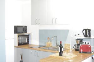 a white kitchen with a sink and a microwave at Amélia in Soulac-sur-Mer