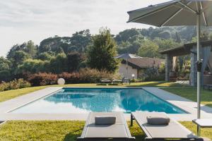 a swimming pool with two lounge chairs and an umbrella at Tenuta Ronco Regio in San Fermo della Battaglia