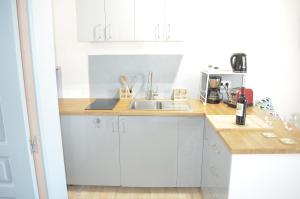 a kitchen with white cabinets and a sink at Amélia in Soulac-sur-Mer