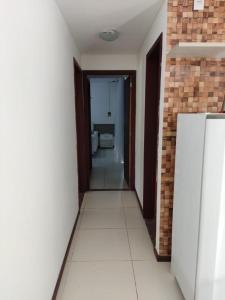 a hallway of a room with a refrigerator and a bathroom at Villas Supreme Apartamentos in Maceió