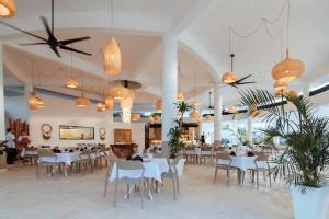 a restaurant with white tables and chairs and potted plants at Moderno Apartamento Frente Al Mar in La Iglesia