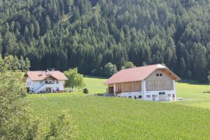 a white barn with a red roof on a green field at Beikircherhof in San Lorenzo di Sebato