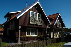 Casa marrón con ventanas y valla en Vila Lotmiškis, en Nida