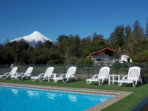 un gruppo di sedie bianche sedute accanto alla piscina di Cabañas Inadeqin a La Ensenada