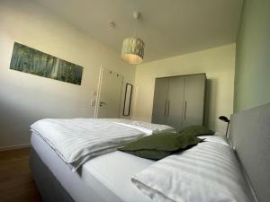 a bedroom with a large bed with white sheets and green pillows at Haus Sonnenhang in Hauenstein