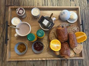 a wooden tray with bread and other breakfast foods at Studio de charme in Bois-Grenier