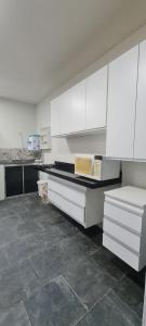 a kitchen with white cabinets and a counter with a microwave at Quartos Individuais Privativos in Barueri