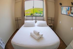 a white towel sitting on a bed with a window at Hotel Maria da Fé in Aparecida