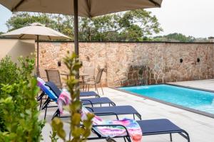 a group of chairs and umbrellas next to a swimming pool at Pousada Caminho do Bosque in Bombinhas