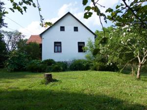 una casa blanca en un campo verde con un tronco de árbol en Hétrét Vendégház, en Kercaszomor