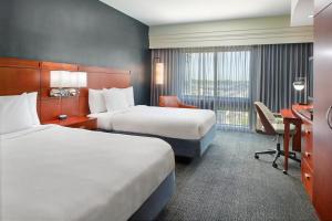 华纳罗宾斯沃纳罗宾斯万怡酒店的一间酒店房间，里面有两张床和一张桌子。