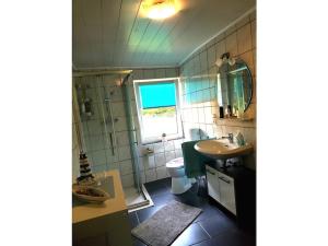 a bathroom with a sink and a toilet and a window at Country House East Frisia in Großheide