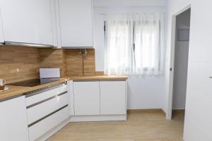 a white kitchen with white cabinets and a window at Casa Callejón de las Morenicas in Cazorla