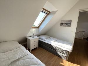 Un dormitorio abuhardillado con dos camas y una ventana. en luxury holiday apartment Duhnenblick, en Duhnen