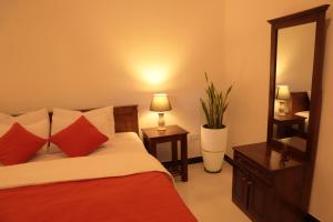 a bedroom with a bed with red and white pillows at The Cattleya Guest House Sigiriya in Sigiriya