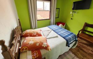 a bedroom with green walls and a bed with pillows at Suítes Cantinho Gostoso in Lavras Novas