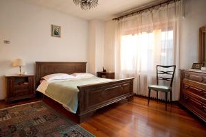 a bedroom with a bed and a chair and a window at B&B Colli's Dolomites in Belluno