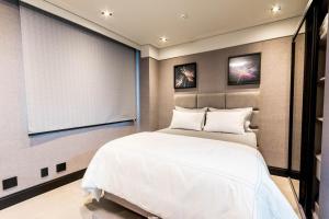 巴鲁埃里Flat com lazer, Wi-Fi e otima localizacao的卧室配有一张白色的大床和屏幕 更多19张照片