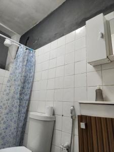 a bathroom with a toilet and a blue shower curtain at Katai in Salvador