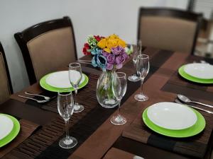 a wooden table with plates and a vase of flowers at Lola's Haven - 75" Screen, Heated Pool, Gym, Views in Nairobi