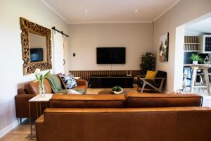 a living room with brown leather furniture and a flat screen tv at Rustfontein Guest Farm and Venue in Malmesbury
