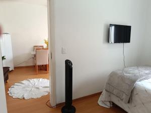 a room with a bed and a television on a wall at Ap 3 Ouro Pret com piscina aquecimento solar e churrasqueira in Ouro Preto