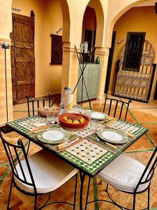 a table with plates and a bowl of fruit on it at Riad Dar El Hana in Taroudant
