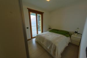 een slaapkamer met een wit bed en een raam bij Residence degli Oleandri 4B in Argegno