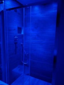 une salle de bain avec une douche en verre avec éclairage bleu dans l'établissement BELOVED luxury room, à Corato