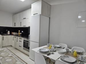 eine Küche mit einem Tisch und einem weißen Kühlschrank in der Unterkunft Lilium in Cazin